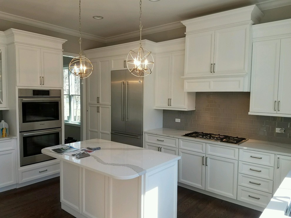 Example of a mid-sized transitional l-shaped dark wood floor enclosed kitchen design in Chicago with an undermount sink, shaker cabinets, white cabinets, quartz countertops, gray backsplash, subway tile backsplash, stainless steel appliances and an island