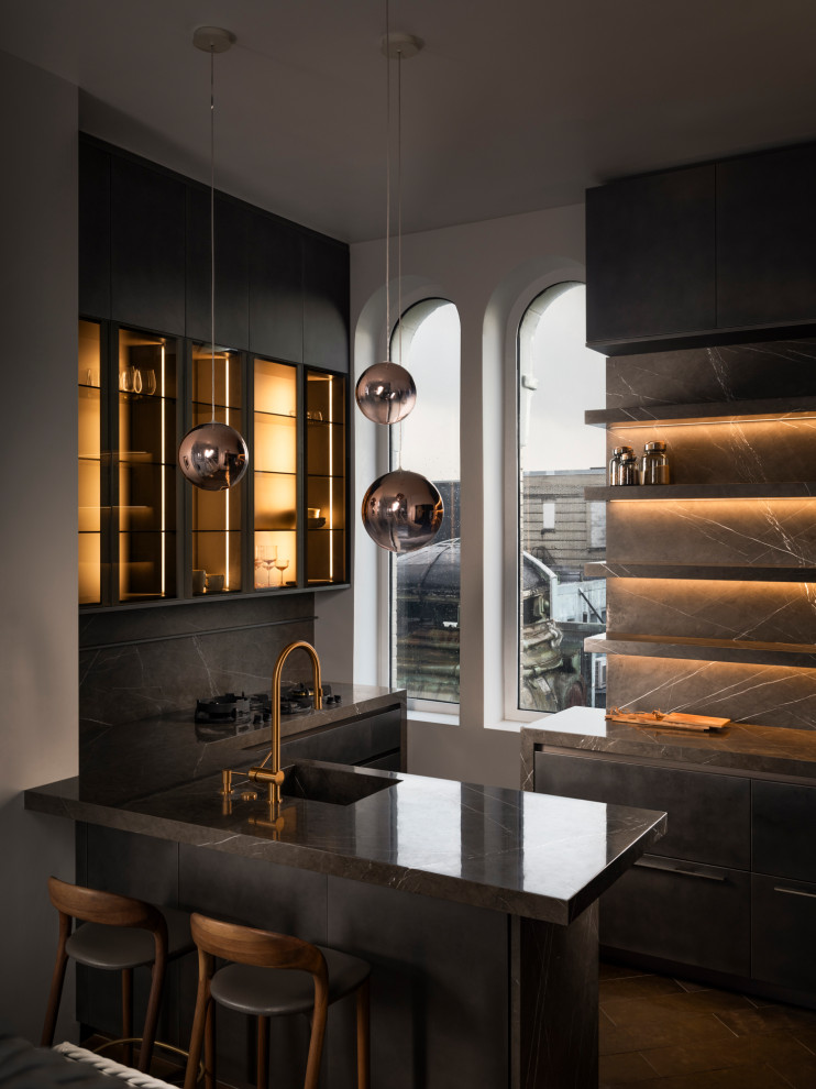 Small modern kitchen with an integrated sink, flat-panel cabinets, black cabinets, marble benchtops, black splashback, marble splashback, panelled appliances, a peninsula, brown floor and black benchtop.