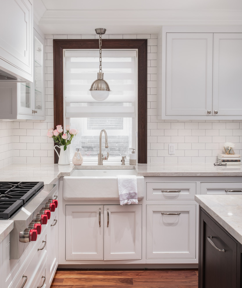 Mid-sized transitional u-shaped medium tone wood floor and brown floor eat-in kitchen photo in Toronto with a farmhouse sink, recessed-panel cabinets, gray cabinets, quartzite countertops, white backsplash, subway tile backsplash, stainless steel appliances, an island and beige countertops
