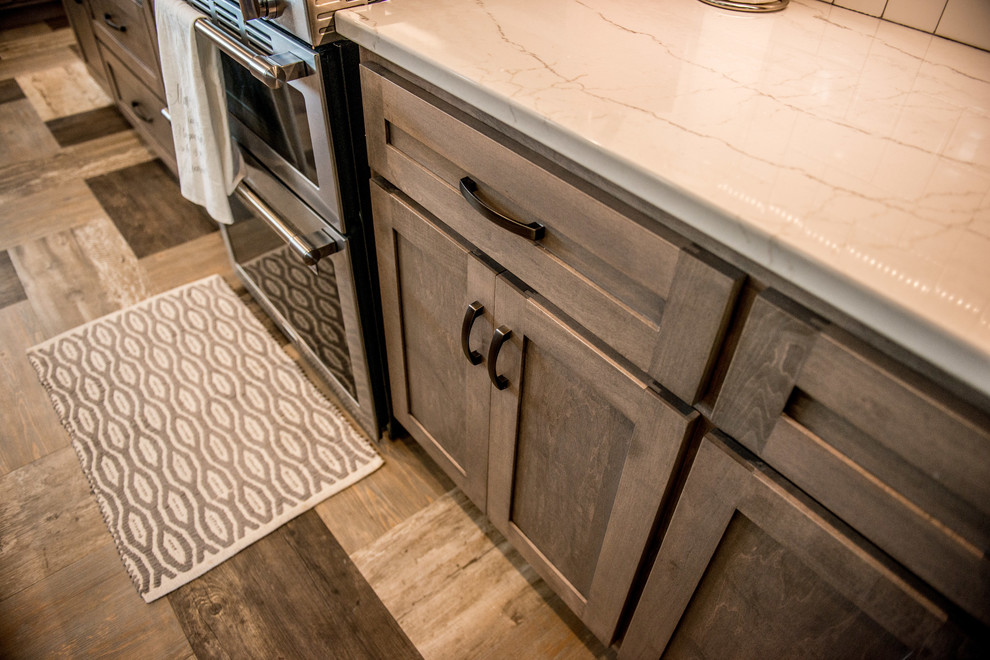 Inspiration for a large transitional l-shaped vinyl floor and multicolored floor open concept kitchen remodel with a farmhouse sink, shaker cabinets, gray cabinets, quartz countertops, white backsplash, subway tile backsplash, stainless steel appliances, an island and white countertops