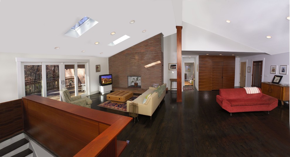 Contemporary open concept family room in Atlanta with white walls, dark hardwood floors and a corner tv.