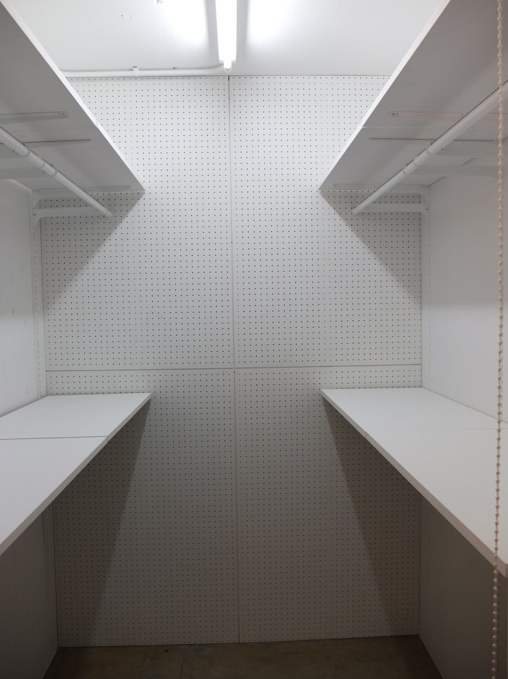 Immagine di una piccola cabina armadio unisex moderna con pavimento in cemento e travi a vista