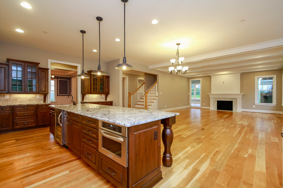 Example of a classic medium tone wood floor kitchen design in Baltimore with a farmhouse sink, granite countertops, gray backsplash, ceramic backsplash, paneled appliances and an island