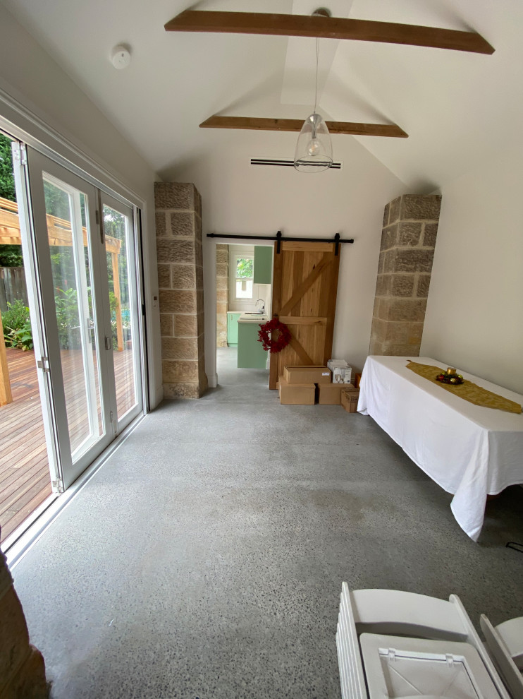 Inspiration for a mid-sized traditional enclosed living room in Sydney with white walls, concrete floors, a concealed tv, multi-coloured floor and vaulted.