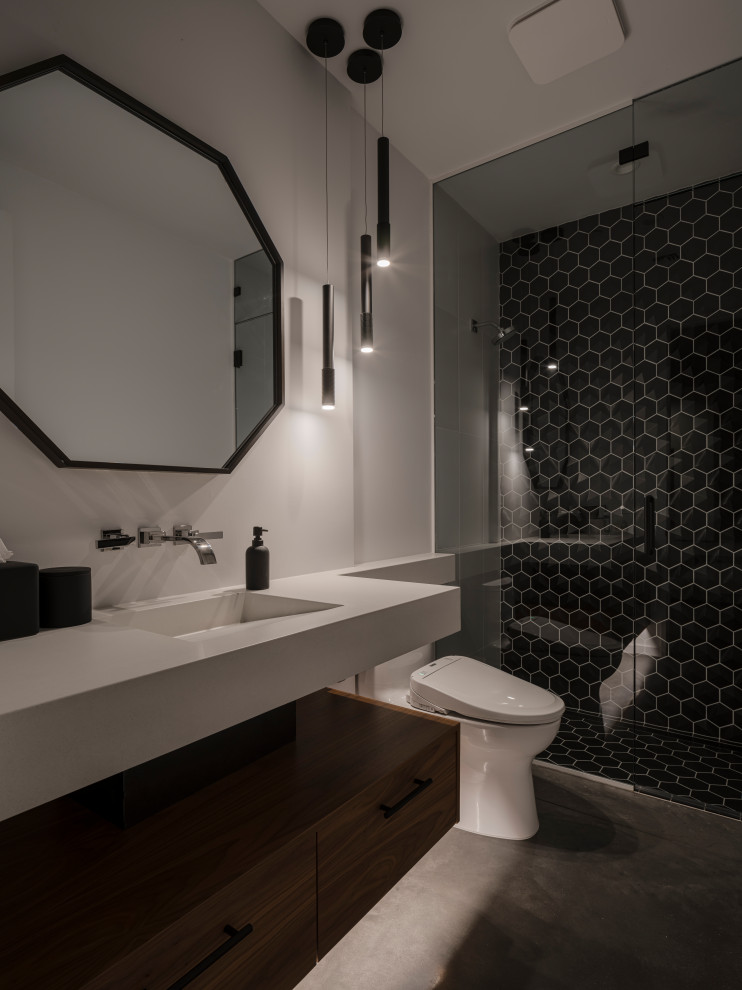 На фото: туалет в стиле модернизм с керамической плиткой, подвесной тумбой, черной плиткой, бетонным полом, монолитной раковиной и столешницей из бетона