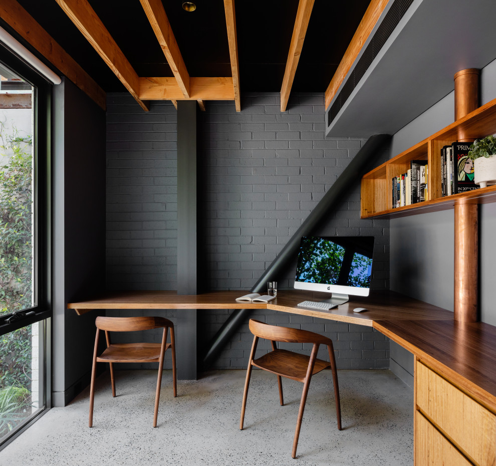 Idéer för ett mellanstort industriellt hemmabibliotek, med grå väggar, betonggolv och ett inbyggt skrivbord