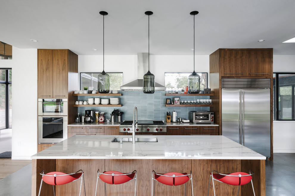 This is an example of a contemporary galley eat-in kitchen in Austin with a single-bowl sink, flat-panel cabinets, grey splashback, stone tile splashback, stainless steel appliances, concrete floors, with island and dark wood cabinets.