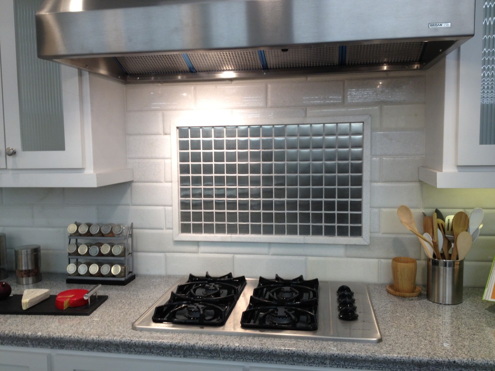 Example of a mid-sized transitional l-shaped enclosed kitchen design in Cincinnati with glass-front cabinets, white cabinets, quartz countertops, white backsplash, subway tile backsplash and stainless steel appliances