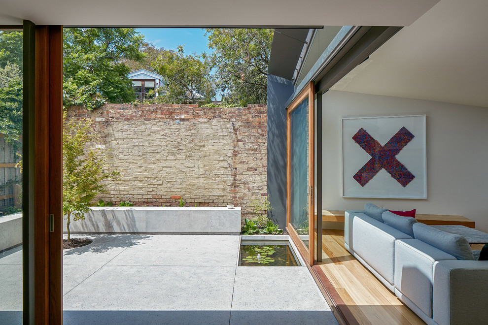 Photo of a small contemporary courtyard partial sun xeriscape for fall in Melbourne with with raised garden bed and natural stone pavers.