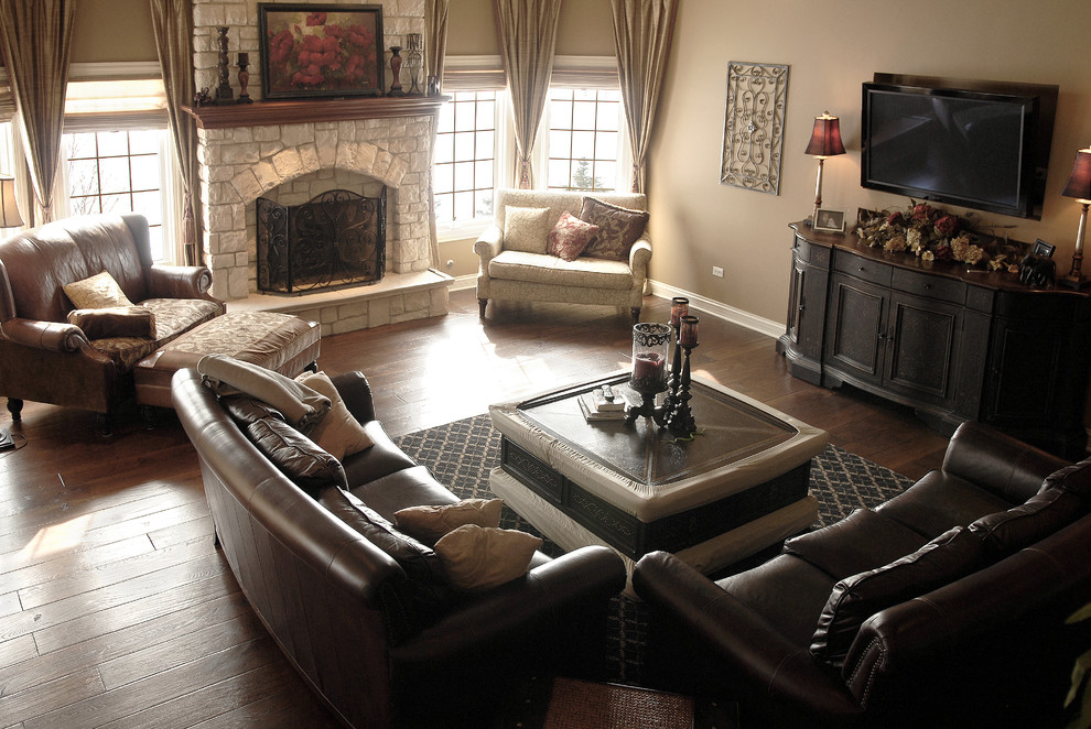 Großes Klassisches Wohnzimmer mit beiger Wandfarbe, dunklem Holzboden, Kamin, Kaminumrandung aus Stein, TV-Wand, braunem Boden und Kassettendecke in Chicago
