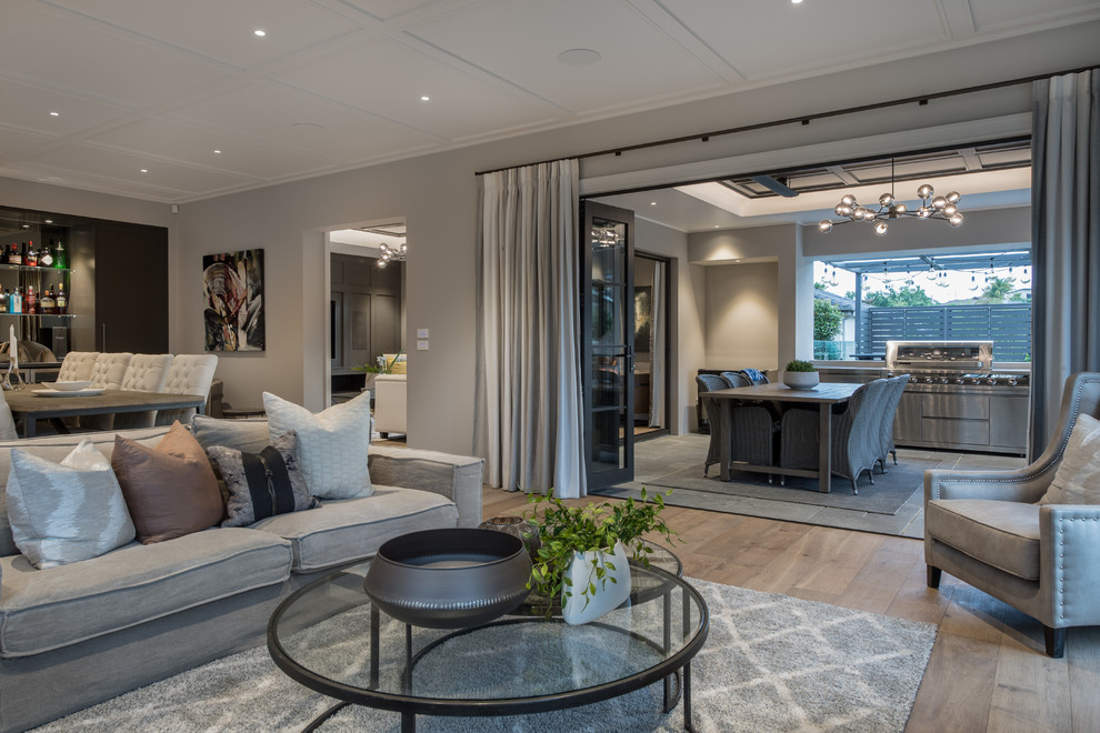 Large open concept living room in Auckland with grey walls, medium hardwood floors, a wall-mounted tv, a ribbon fireplace, a tile fireplace surround and brown floor.