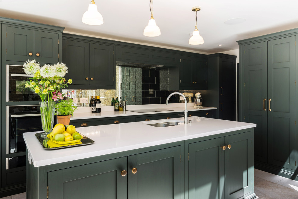 Large traditional l-shaped eat-in kitchen in London with shaker cabinets, green cabinets, quartzite benchtops, metallic splashback, panelled appliances, limestone floors, with island, white benchtop, an undermount sink, mirror splashback and beige floor.