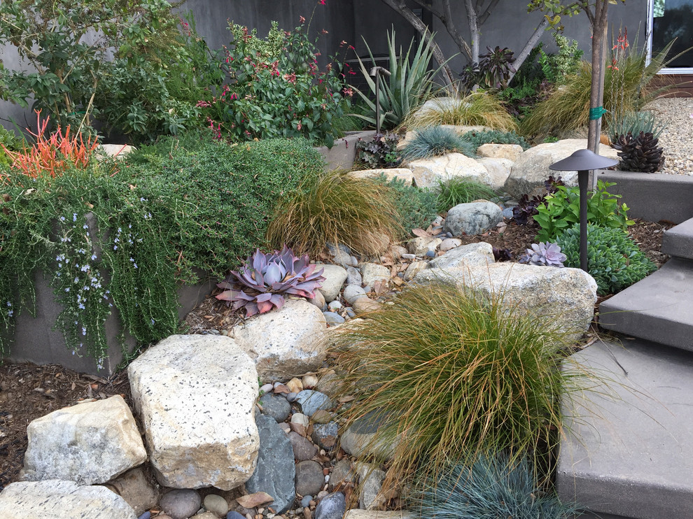 Design ideas for a small midcentury side yard xeriscape in Los Angeles with a retaining wall and gravel.