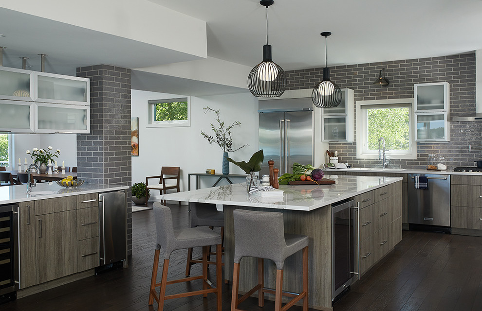 Example of a transitional dark wood floor and brown floor kitchen design in Grand Rapids with flat-panel cabinets, gray backsplash, subway tile backsplash, stainless steel appliances and an island
