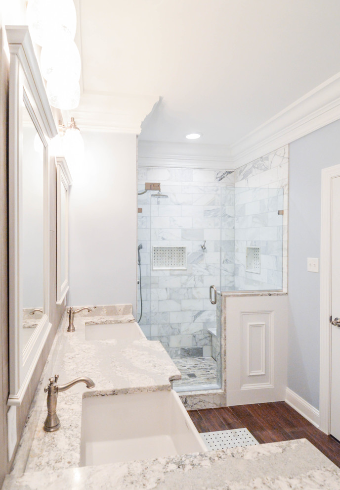 This is an example of a mid-sized transitional master bathroom in Wilmington with raised-panel cabinets, grey cabinets, an alcove shower, a two-piece toilet, white tile, marble, grey walls, dark hardwood floors, a drop-in sink, engineered quartz benchtops, brown floor, a hinged shower door and white benchtops.