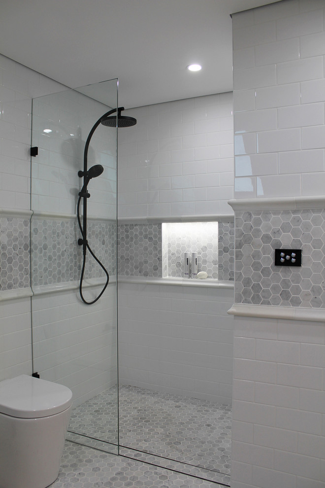 Inspiration for a mid-sized contemporary master bathroom in Sydney with shaker cabinets, white cabinets, a freestanding tub, an open shower, a wall-mount toilet, white tile, white walls, marble floors, an undermount sink, marble benchtops and subway tile.