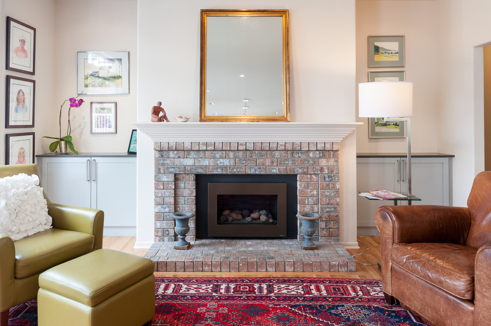 This is an example of a mid-sized traditional open concept living room in Seattle with light hardwood floors, a standard fireplace, a brick fireplace surround and no tv.