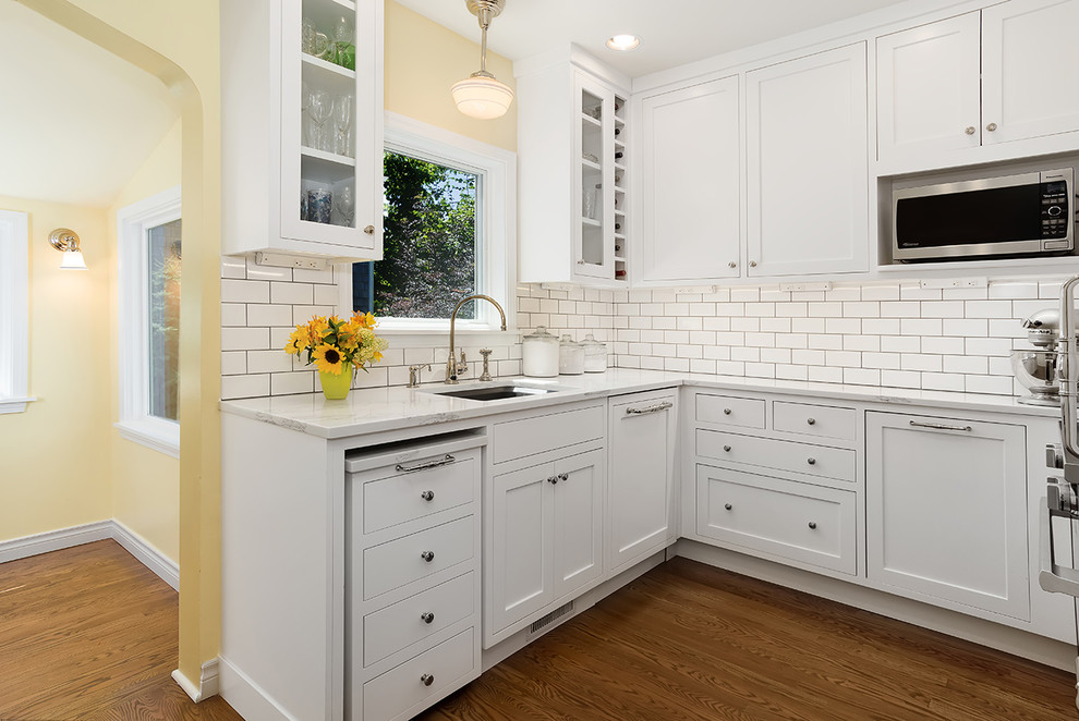 Small traditional u-shaped separate kitchen in Boise with an undermount sink, beaded inset cabinets, white cabinets, quartz benchtops, white splashback, subway tile splashback, panelled appliances, medium hardwood floors, no island, brown floor and white benchtop.
