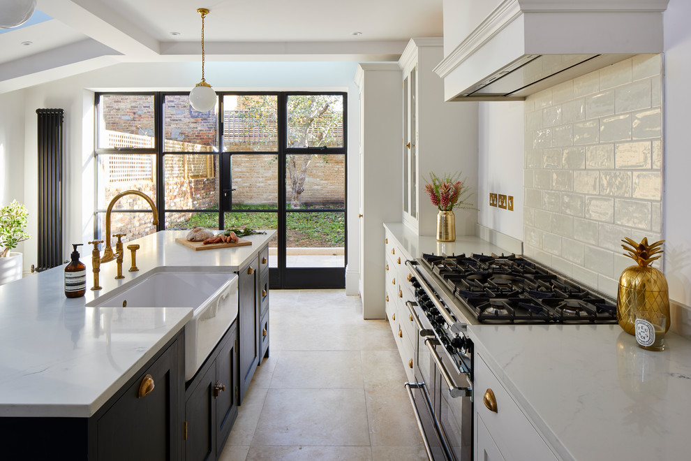 Photo of a transitional l-shaped eat-in kitchen in London with a farmhouse sink, shaker cabinets, white cabinets, white splashback, black appliances, with island, beige floor and white benchtop.