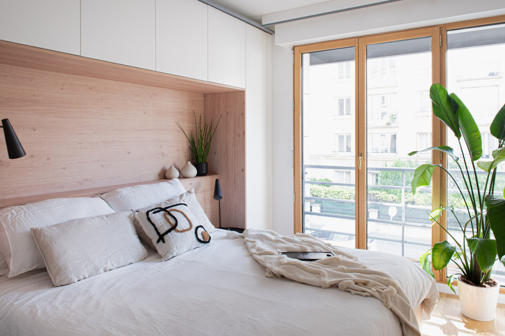 Contemporary bedroom in Paris with white walls, medium hardwood floors and brown floor.