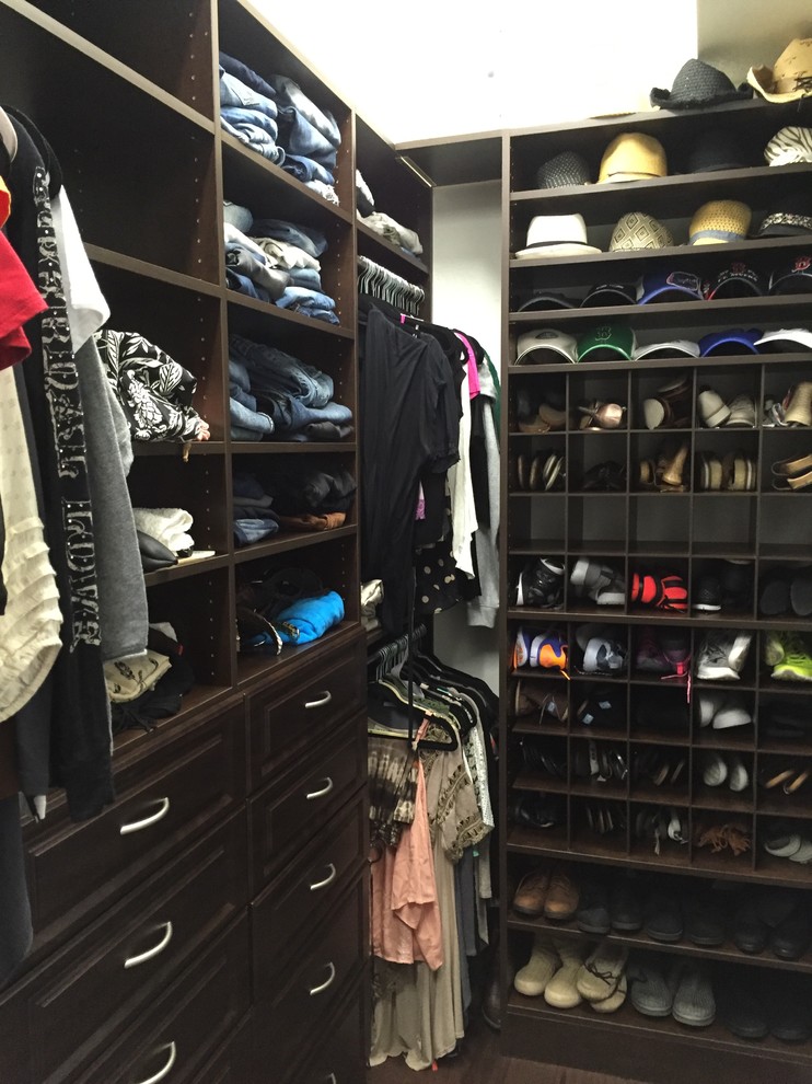 Photo of a mid-sized traditional gender-neutral walk-in wardrobe in Miami with raised-panel cabinets, dark wood cabinets and carpet.