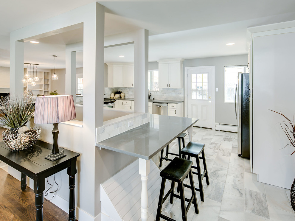 Inspiration for a mid-sized transitional l-shaped kitchen remodel with an undermount sink, shaker cabinets, white cabinets, white backsplash, stainless steel appliances and a peninsula