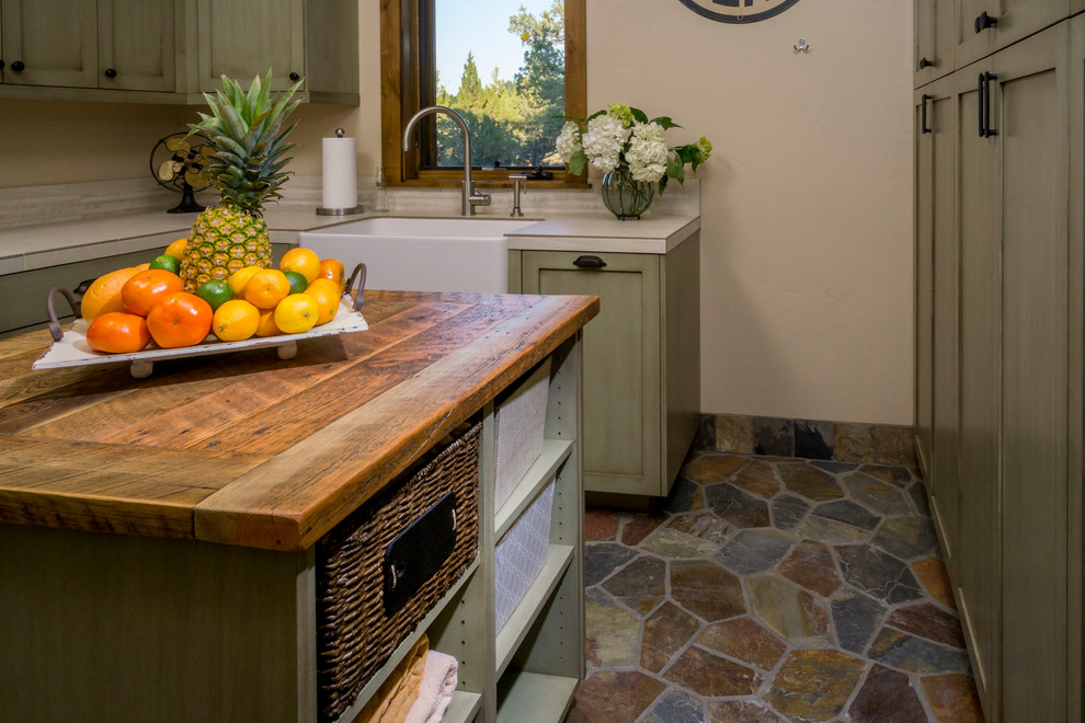 This is an example of a large country u-shaped dedicated laundry room in Other with a farmhouse sink, shaker cabinets, green cabinets, quartz benchtops, beige walls, a side-by-side washer and dryer, multi-coloured floor and beige benchtop.