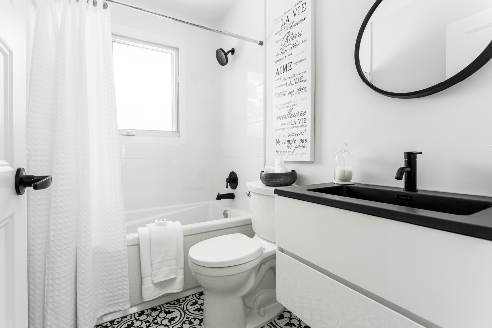 На фото: маленькая ванная комната в стиле кантри с плоскими фасадами, белыми фасадами, ванной в нише, душем над ванной, раздельным унитазом, белой плиткой, керамогранитной плиткой, белыми стенами, полом из керамической плитки, душевой кабиной, врезной раковиной, столешницей из искусственного кварца, черным полом, шторкой для ванной, черной столешницей, тумбой под одну раковину и подвесной тумбой для на участке и в саду