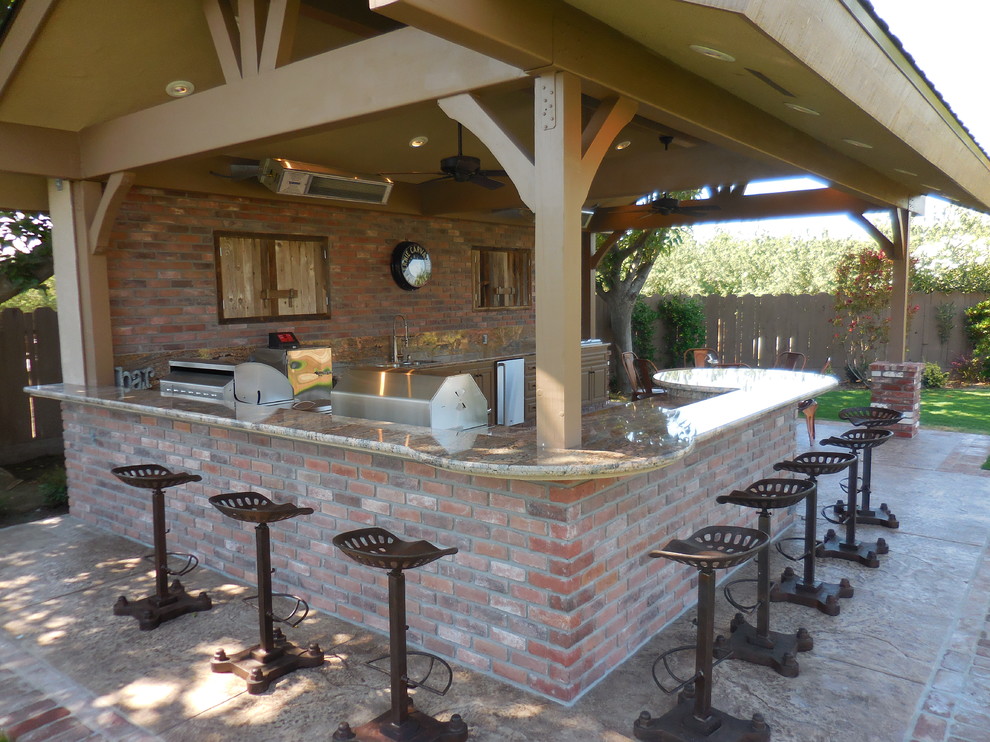 This is an example of a large country backyard patio in Other with an outdoor kitchen, stamped concrete and a pergola.