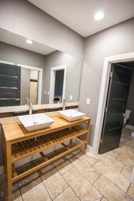 Example of a mid-sized minimalist 3/4 beige tile and porcelain tile porcelain tile bathroom design with open cabinets, light wood cabinets, gray walls, a vessel sink and wood countertops