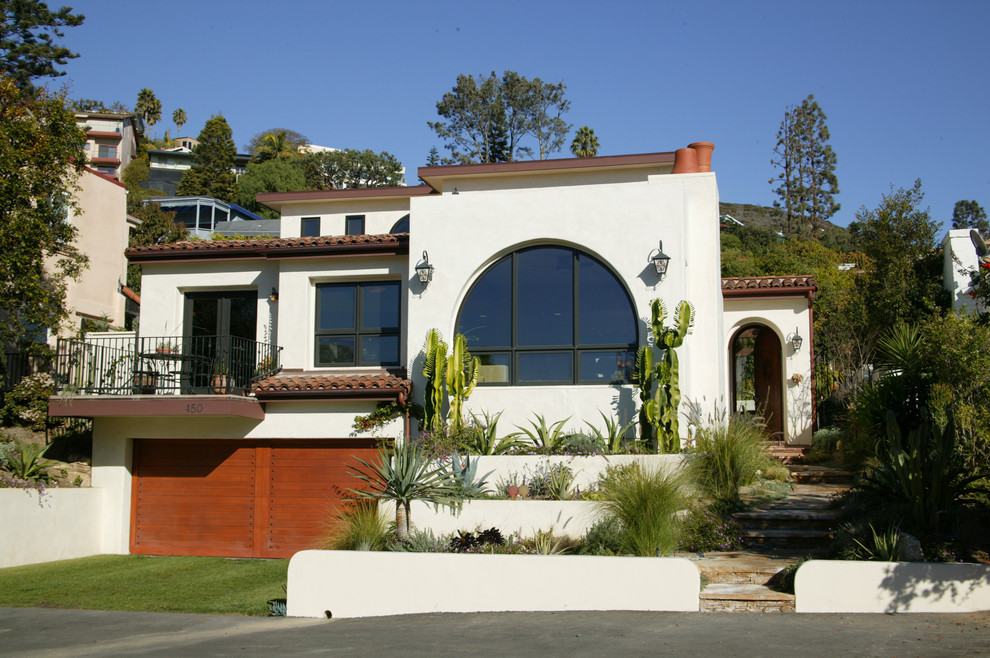 This is an example of a mid-sized mediterranean three-storey stucco white exterior in Orange County with a flat roof.