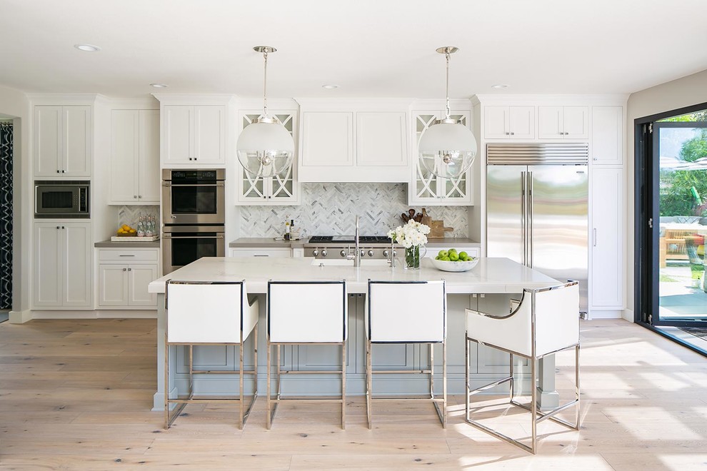 Inspiration for a beach style kitchen in San Diego with shaker cabinets, white cabinets, multi-coloured splashback, stainless steel appliances, light hardwood floors, with island, beige floor and white benchtop.