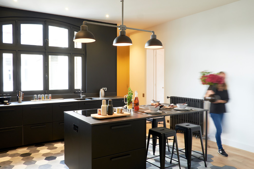 Scandinavian kitchen in London with a double-bowl sink, flat-panel cabinets, black cabinets, with island and multi-coloured floor.