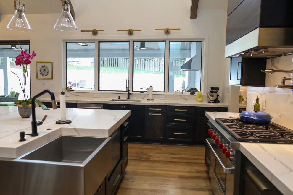 Inspiration for a large transitional u-shaped light wood floor open concept kitchen remodel with a farmhouse sink, flat-panel cabinets, dark wood cabinets, quartz countertops, white backsplash, quartz backsplash, stainless steel appliances, an island and white countertops
