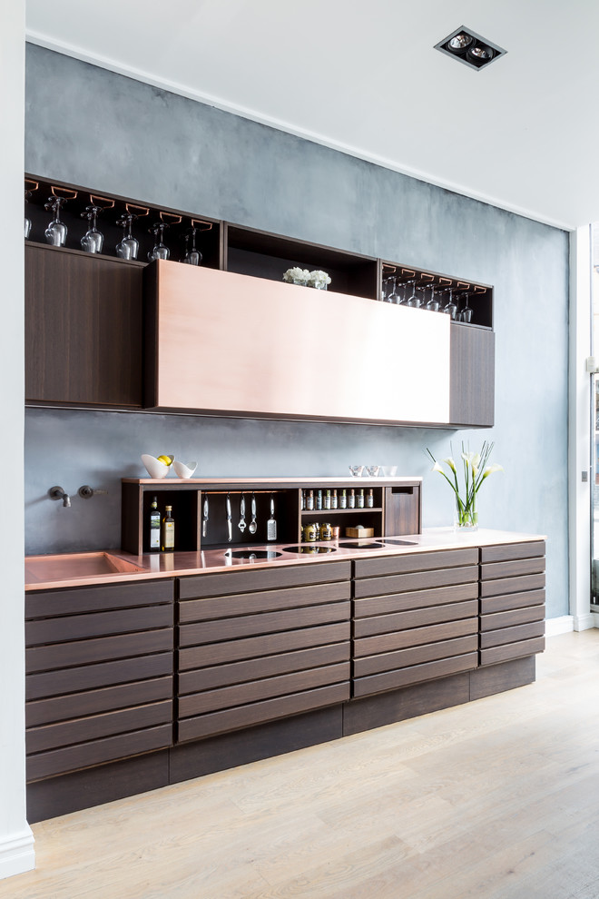 Photo of a small contemporary single-wall open plan kitchen in London with a drop-in sink, flat-panel cabinets, brown cabinets, copper benchtops, grey splashback and no island.