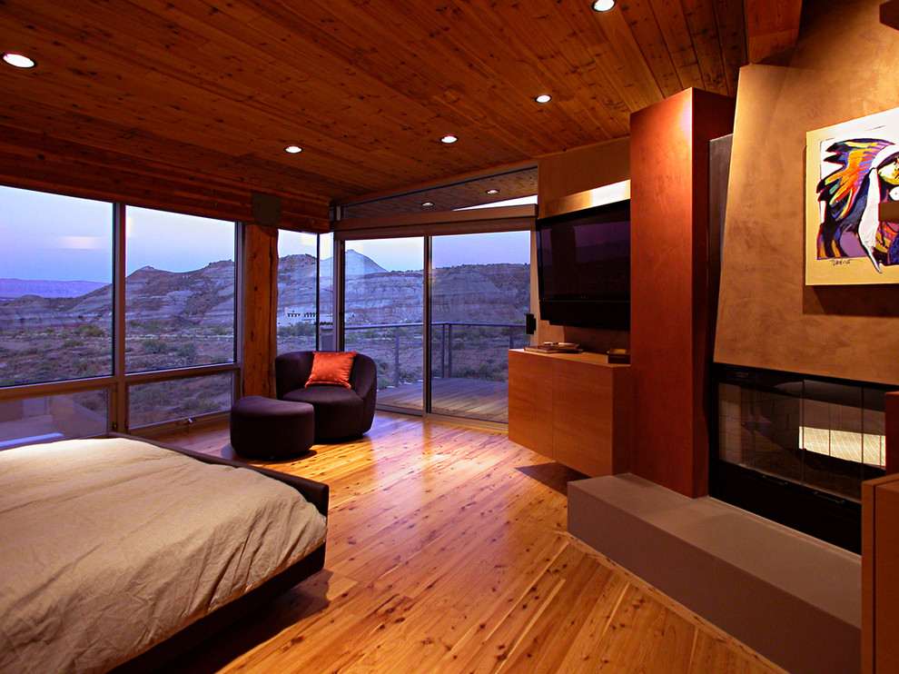 Пример оригинального дизайна: хозяйская спальня в современном стиле с оранжевыми стенами, паркетным полом среднего тона, двусторонним камином и фасадом камина из металла