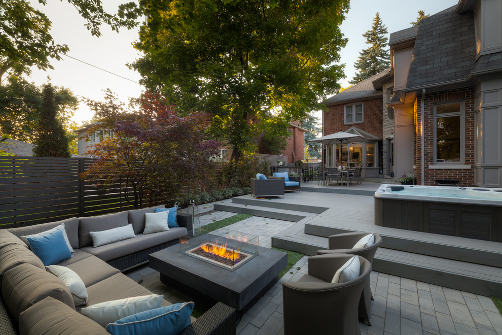 Large contemporary backyard rectangular aboveground pool in Toronto with a hot tub and decking.