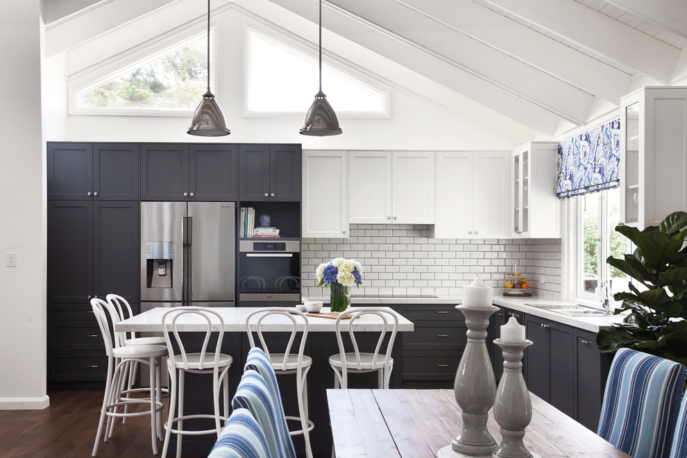 Inspiration for a large beach style l-shaped eat-in kitchen in Sydney with a double-bowl sink, shaker cabinets, black cabinets, white splashback, subway tile splashback, stainless steel appliances, dark hardwood floors, with island and brown floor.