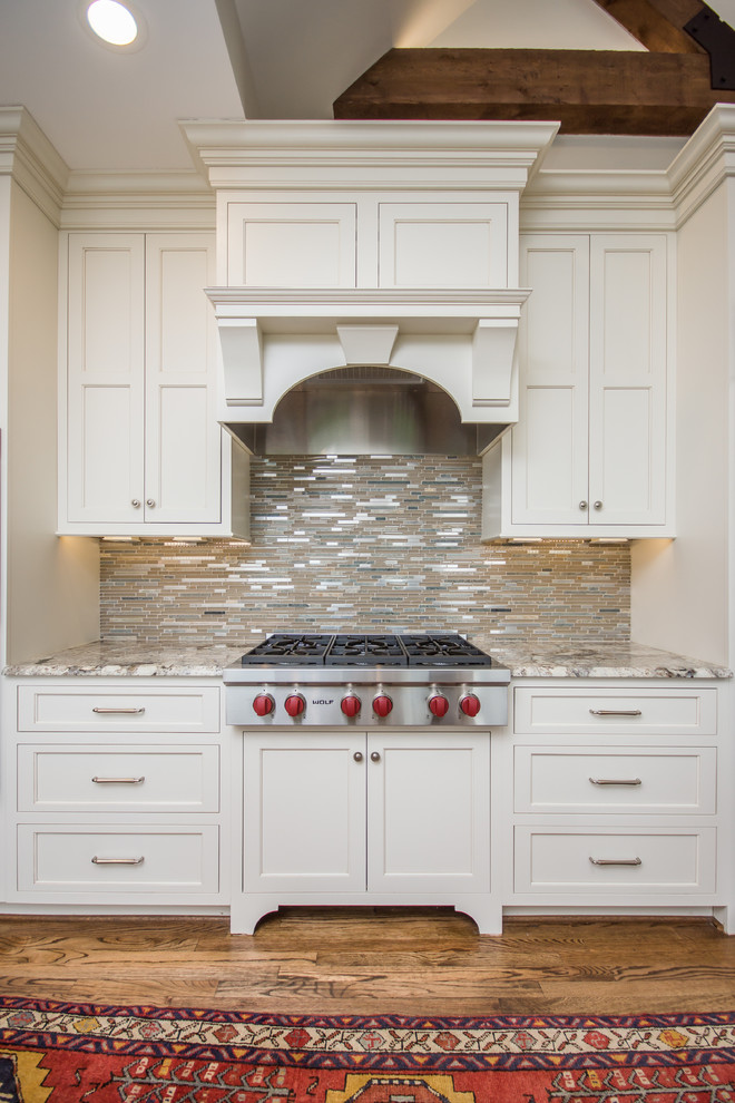 Inspiration for a huge transitional l-shaped medium tone wood floor eat-in kitchen remodel in Birmingham with an undermount sink, recessed-panel cabinets, white cabinets, granite countertops, multicolored backsplash, glass tile backsplash, stainless steel appliances and an island