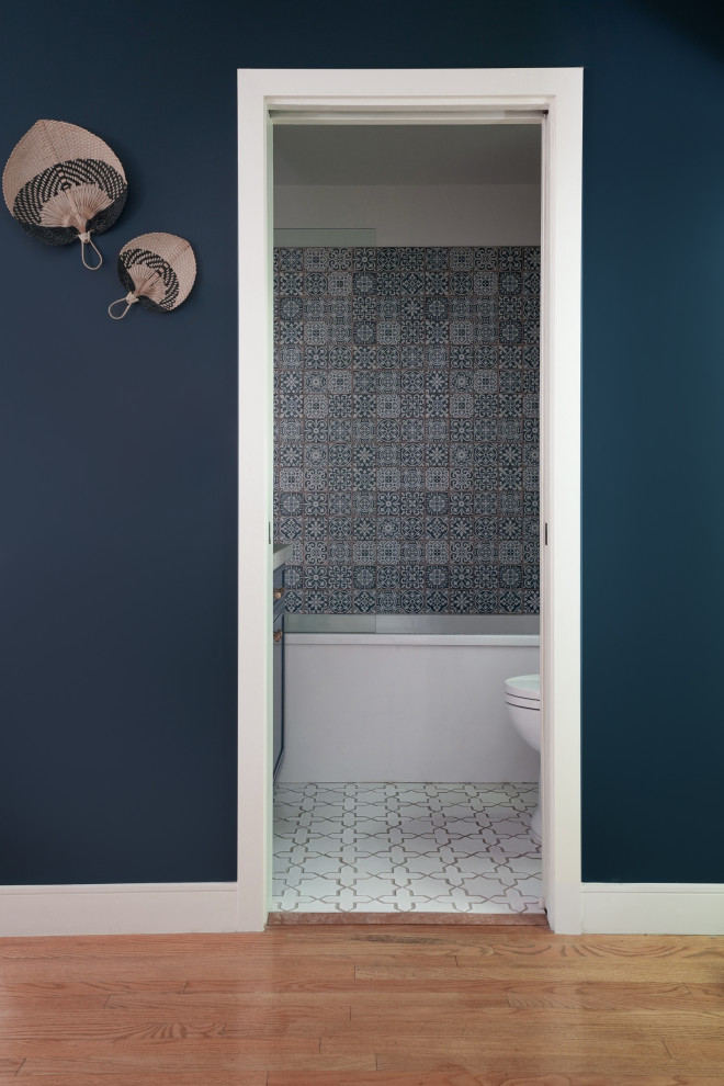 На фото: маленькая ванная комната с синими фасадами, ванной в нише, душем над ванной, унитазом-моноблоком, синей плиткой, керамической плиткой, белыми стенами, полом из керамической плитки, врезной раковиной, столешницей из известняка, белым полом, душем с распашными дверями, серой столешницей, тумбой под одну раковину и встроенной тумбой для на участке и в саду с