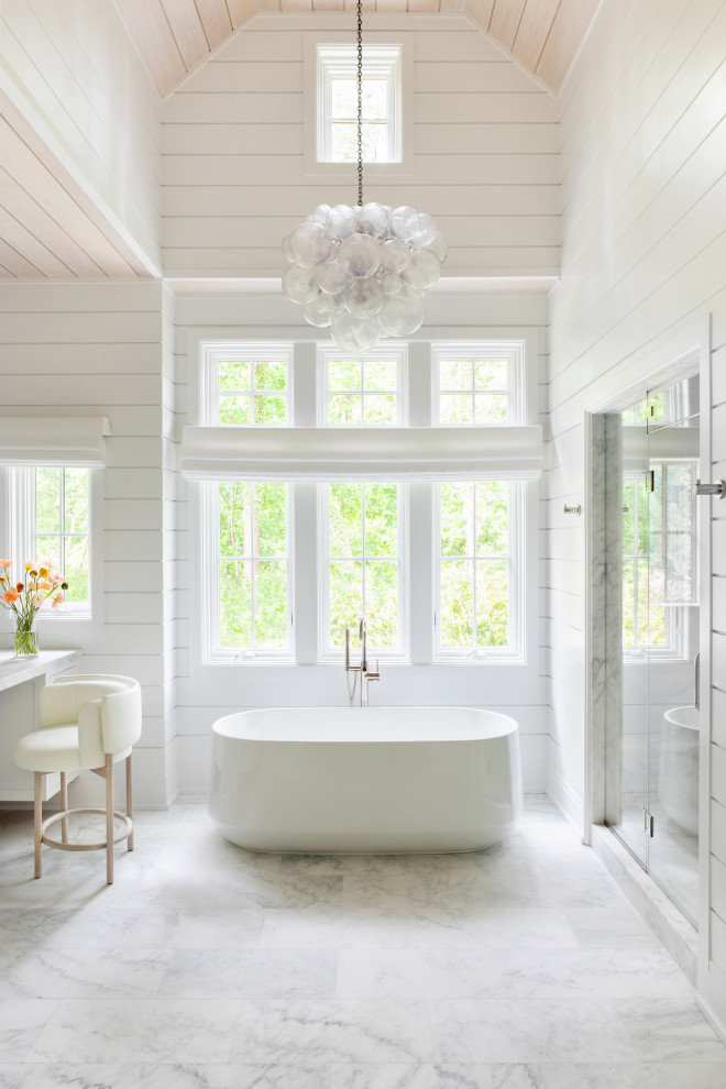 Design ideas for an expansive transitional master bathroom in New York with beaded inset cabinets, white cabinets, a freestanding tub, an alcove shower, white walls, marble floors, an integrated sink, marble benchtops, white floor, a hinged shower door, white benchtops, a double vanity, a built-in vanity, vaulted and panelled walls.