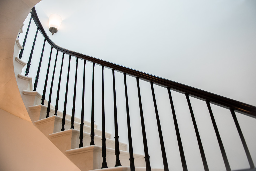 Design ideas for a classic u-shaped metal railing staircase in London with limestone treads and limestone risers.