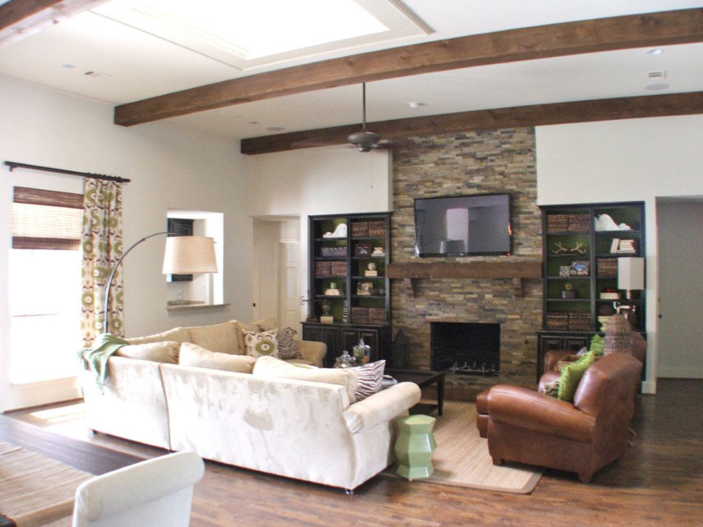 Inspiration for a large transitional open concept living room in Dallas with white walls, dark hardwood floors, a standard fireplace, a stone fireplace surround and a wall-mounted tv.