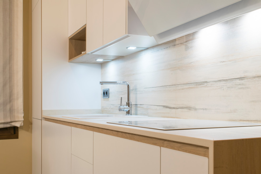 Bild på ett mellanstort funkis vit linjärt vitt kök med öppen planlösning, med en integrerad diskho, släta luckor, vita skåp, bänkskiva i kvarts, vitt stänkskydd, integrerade vitvaror, klinkergolv i keramik, en halv köksö och flerfärgat golv