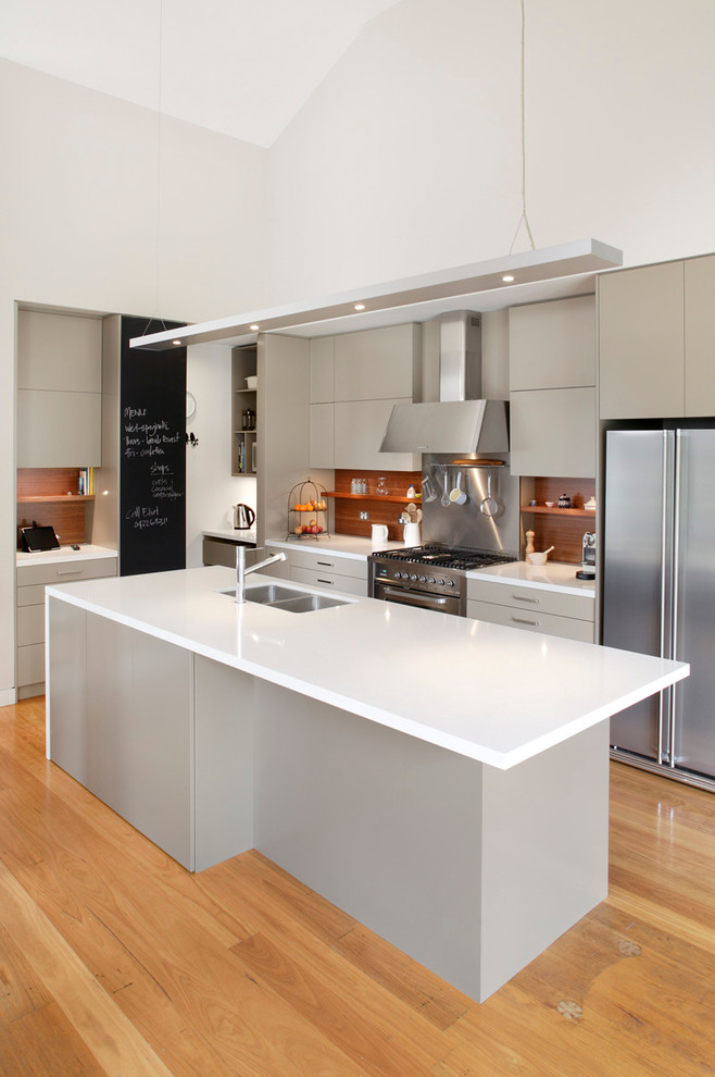 Photo of a mid-sized contemporary l-shaped eat-in kitchen in Sydney with a double-bowl sink, flat-panel cabinets, beige cabinets, brown splashback, stainless steel appliances, quartz benchtops, medium hardwood floors, timber splashback and with island.