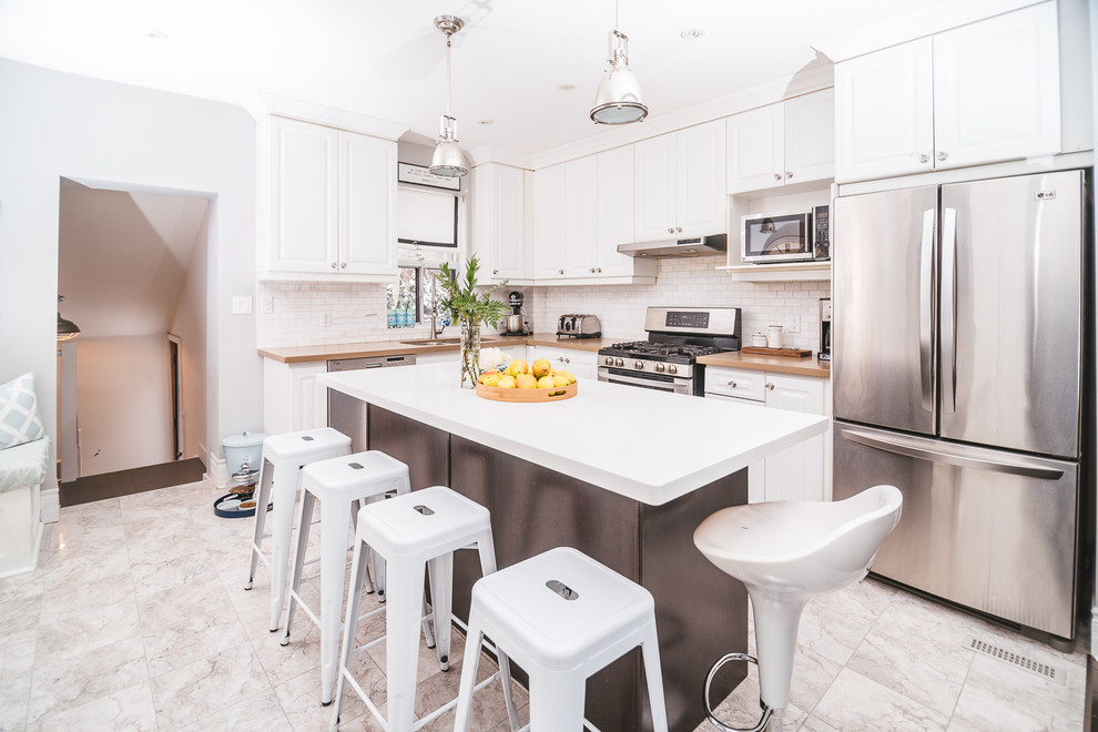 Small country l-shaped eat-in kitchen in Toronto with an undermount sink, shaker cabinets, white cabinets, quartz benchtops, white splashback, subway tile splashback, stainless steel appliances, marble floors, with island and multi-coloured floor.