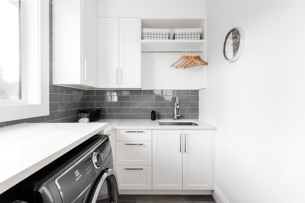 Inspiration for a mid-sized contemporary l-shaped dedicated laundry room in Vancouver with an undermount sink, shaker cabinets, white cabinets, quartz benchtops, porcelain floors, an integrated washer and dryer, grey floor and grey benchtop.