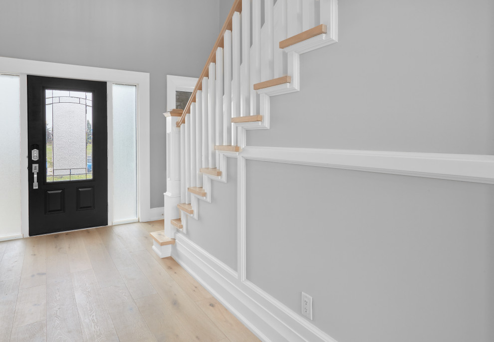 This is an example of a large contemporary foyer in Edmonton with grey walls, light hardwood flooring, a single front door, a black front door, brown floors, a coffered ceiling and wainscoting.