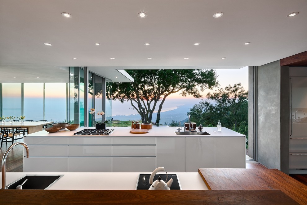 Modern open plan kitchen in Santa Barbara with a drop-in sink, flat-panel cabinets and white cabinets.