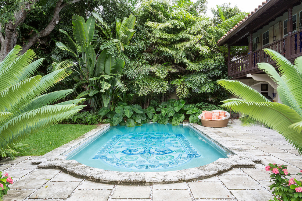 Photo of a mediterranean backyard custom-shaped pool in Miami with concrete pavers.